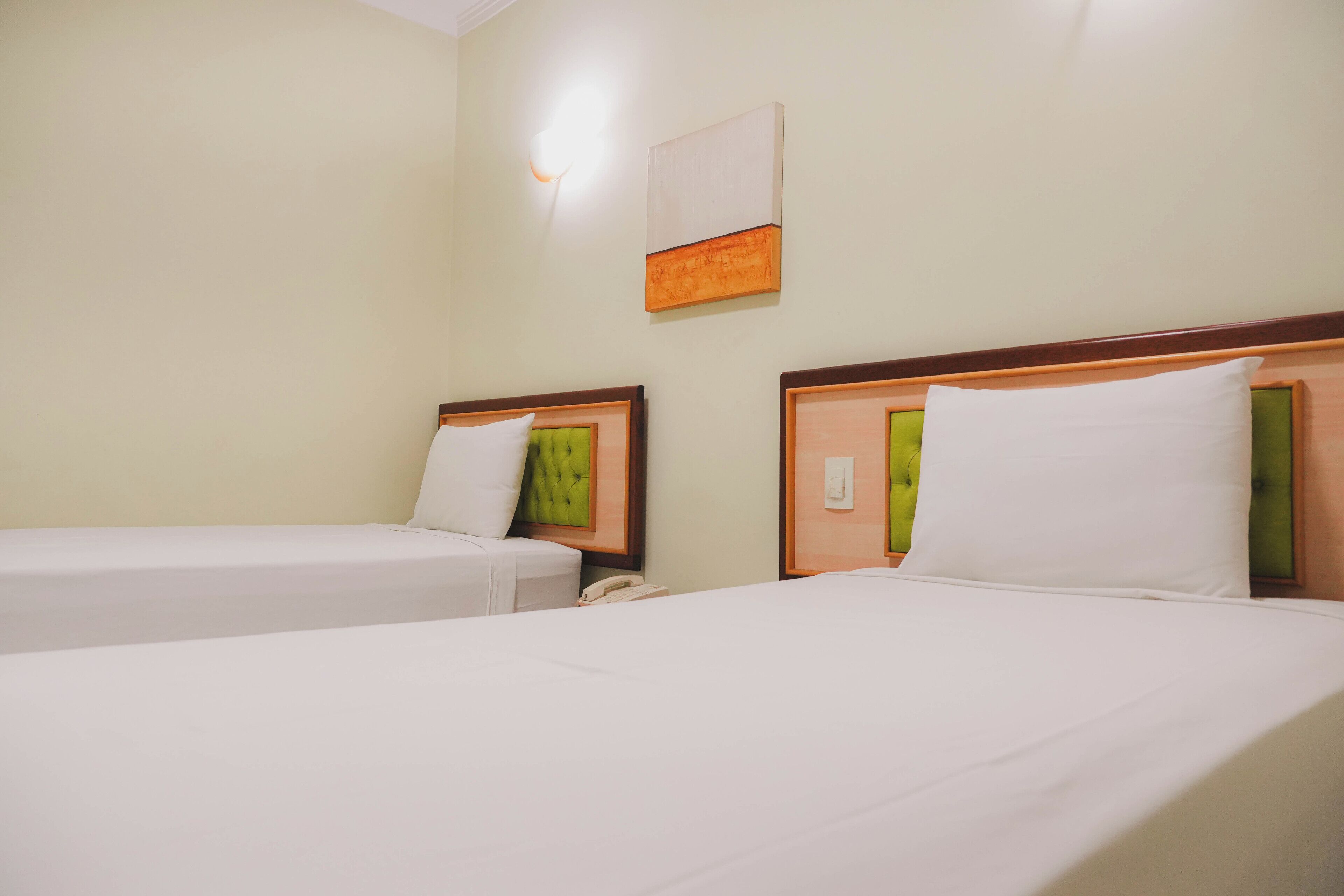 Two single beds with wooden headboards, white bedding, and a wall-mounted light fixture.