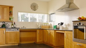A kitchen with wooden cabinets, a Bosch dishwasher, a green toaster, and a stainless steel oven. - Self Catering Holiday Homes Killarney Town Centre (Killarney)