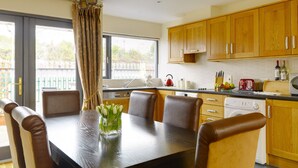 A modern kitchen with wooden cabinets, a dining table with chairs, a kettle, and a toaster. - Self Catering Holiday Homes Killarney Town Centre (Killarney)