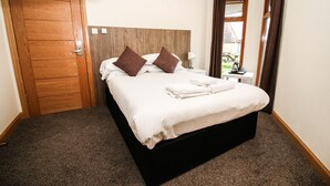 Habitación de hotel con una cama grande, cabecero de madera y vistas al exterior a través de una ventana.