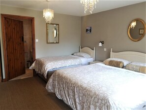 Een slaapkamer met twee bedden, een houten deur, een spiegel en een kroonluchter.