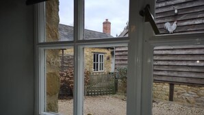 A window with a view of a stone building and a wooden fence. - Holly House Bed & Breakfast (Chipping Campden)