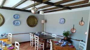 A dining area with a wooden table and chairs, surrounded by walls adorned with blue and gold plates. - Holly House Bed & Breakfast (Chipping Campden)