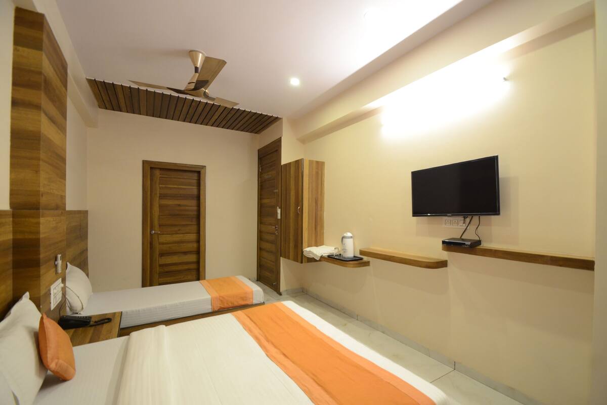 Une chambre d’hôtel équipée d’un lit, d’une télévision, d’un ventilateur de plafond et d’une armoire en bois.