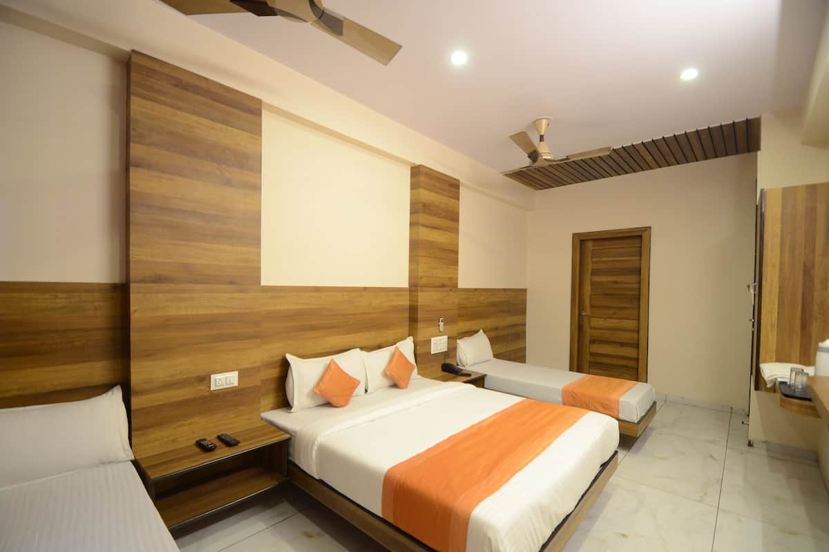 Une chambre d’hôtel avec deux lits, des têtes de lit en bois, un ventilateur de plafond et une porte en bois.