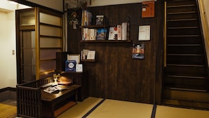 A traditional Japanese room with tatami flooring, a low wooden bench, a bookshelf with various books, and a sign indicating Kyoto. - Gojo Miyabi Inn (Kyoto)