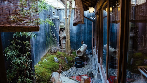 A traditional Japanese garden with a bamboo grove, a stone lantern, and a wooden fence. - Gojo Miyabi Inn (Kyoto)