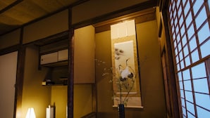 A traditional Japanese room with tatami flooring, a shoji screen, and a vase with branches. - Gojo Miyabi Inn (Kyoto)