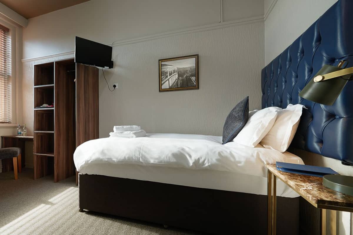 A neatly arranged bedroom with a bed, a chair, a desk, and a bookshelf.