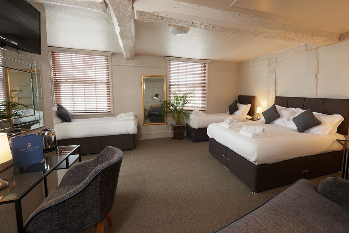 A hotel room with two beds, a desk, a chair, and a television.