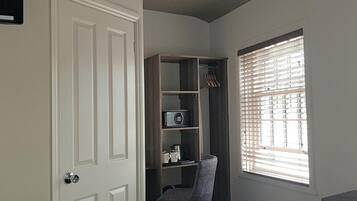 Un dormitorio con armario, una silla, una ventana con persianas y una puerta.