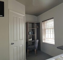 Un dormitorio con armario, una silla, una ventana con persianas y una puerta.