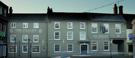 A building with multiple windows and a sign reading "The Falcon Hotel, Restaurant & Bar".