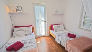 Un dormitorio con dos camas, cada una con una toalla rosa y un estante en la pared con una frase motivacional.
