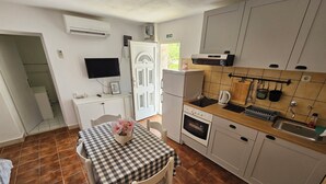 Una cocina compacta con una mesa de comedor, horno integrado, pileta y televisor montado en la pared.