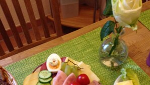 Une table garnie d’une variété d’aliments, notamment du fromage, du jambon, des tomates et des raisins.