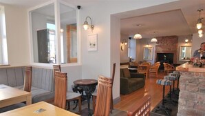 A restaurant with wooden tables and chairs, a fireplace, and a bar area. - The Lion and The Lamb (Seascale)