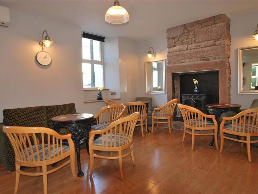 A cozy living room with a fireplace, wooden chairs, a sofa, and a round table.
