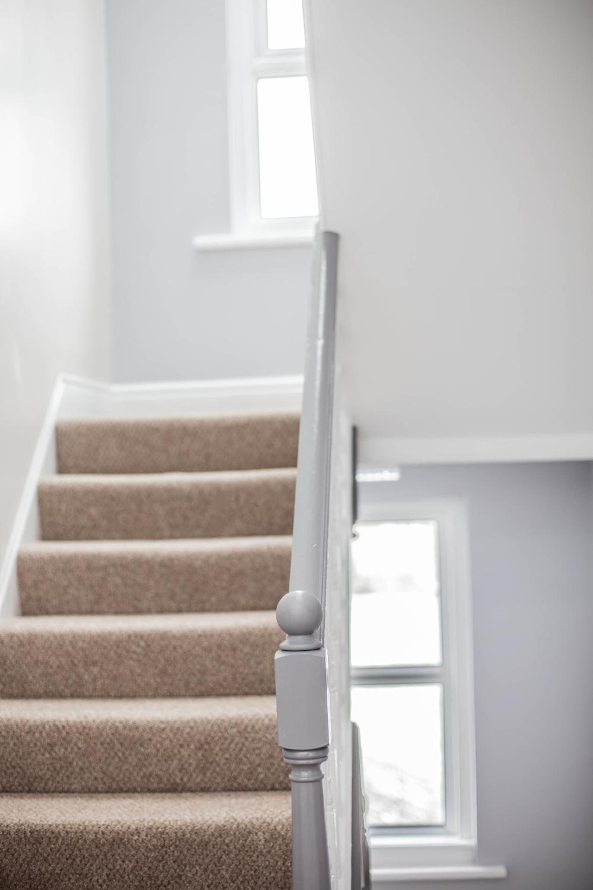 A staircase with beige carpeted steps and white handrails.