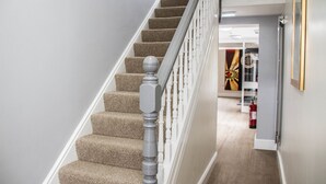 A carpeted staircase with white balusters and a wooden handrail. - Keld Green House (Seascale)