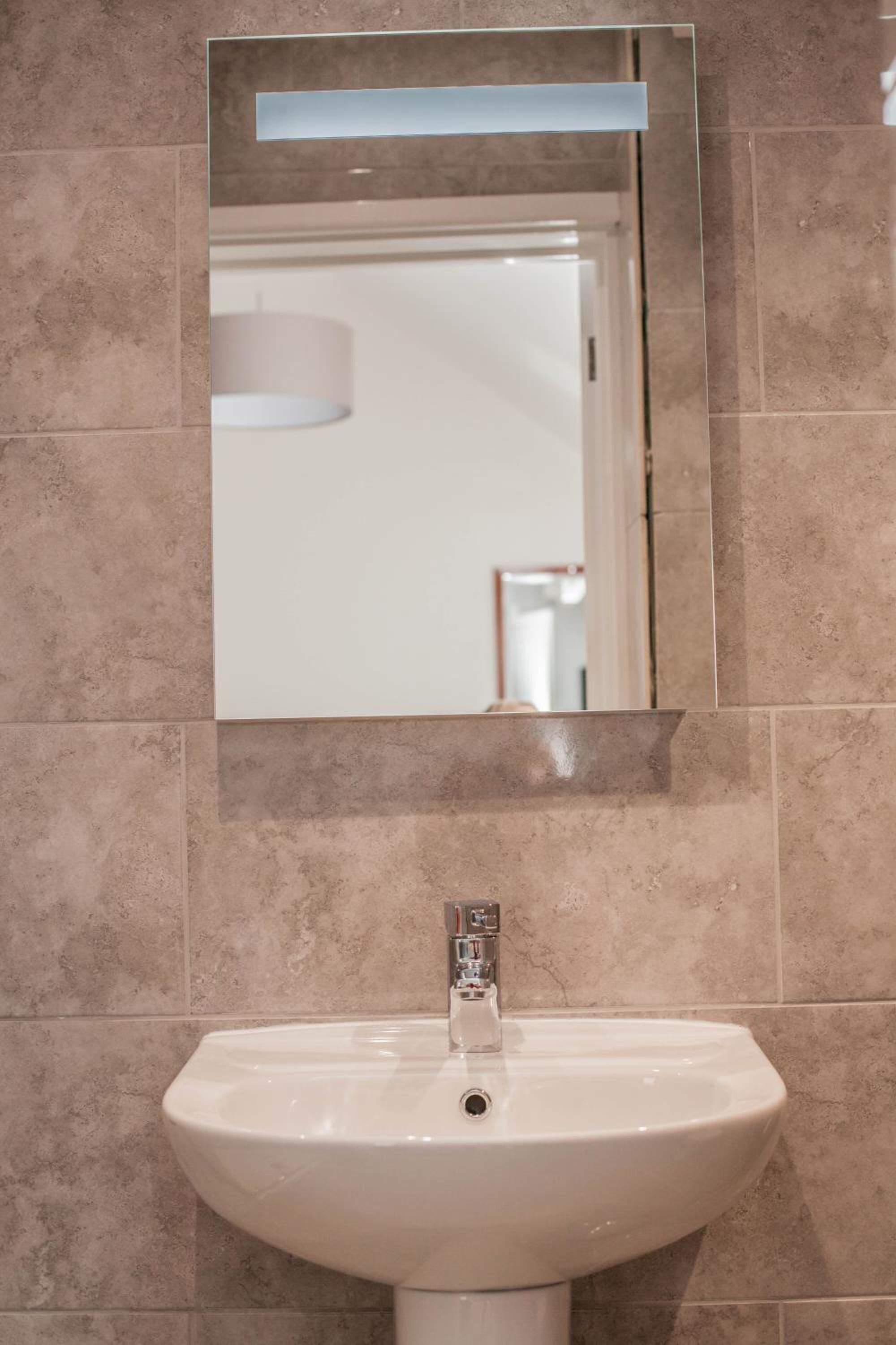 A bathroom with a white sink and a mirror above it.