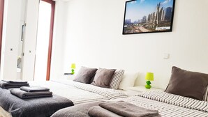 Habitación de hotel con dos camas, ropa de cama a rayas y una fotografía de un paisaje urbano en la pared.