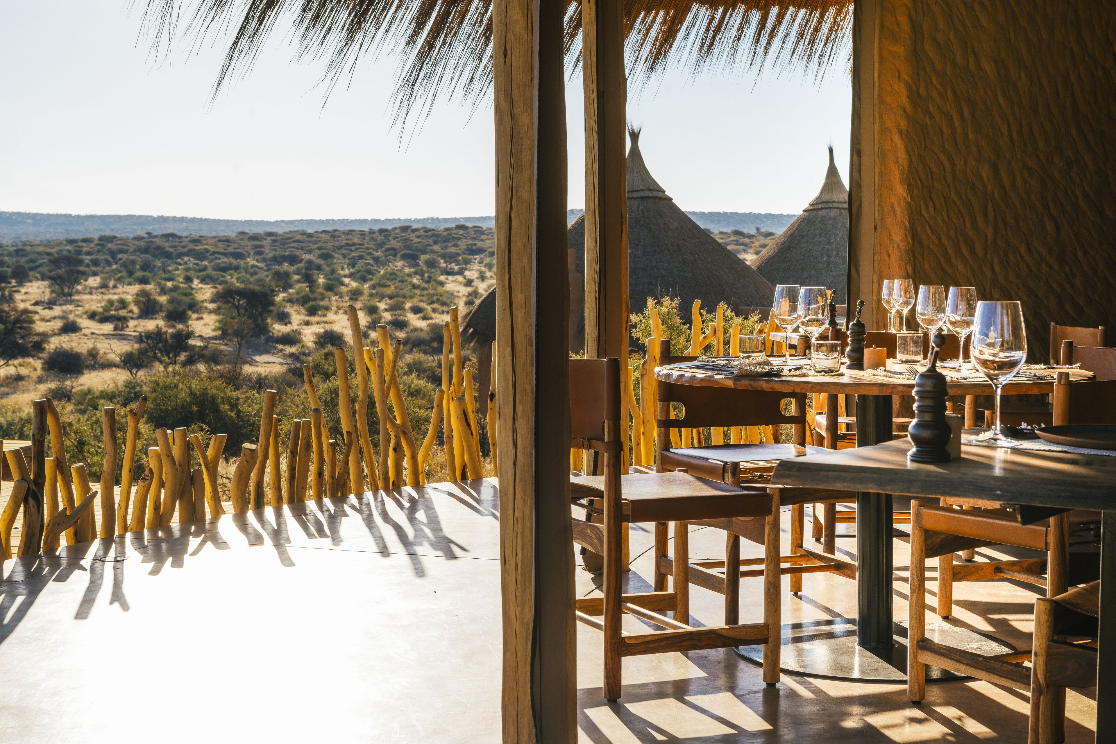 Un área de comedor al aire libre con vistas al desierto y chozas tradicionales.