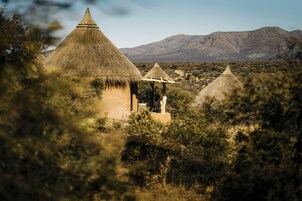 A thatched-roof structure with a small pavilion in a natural setting.