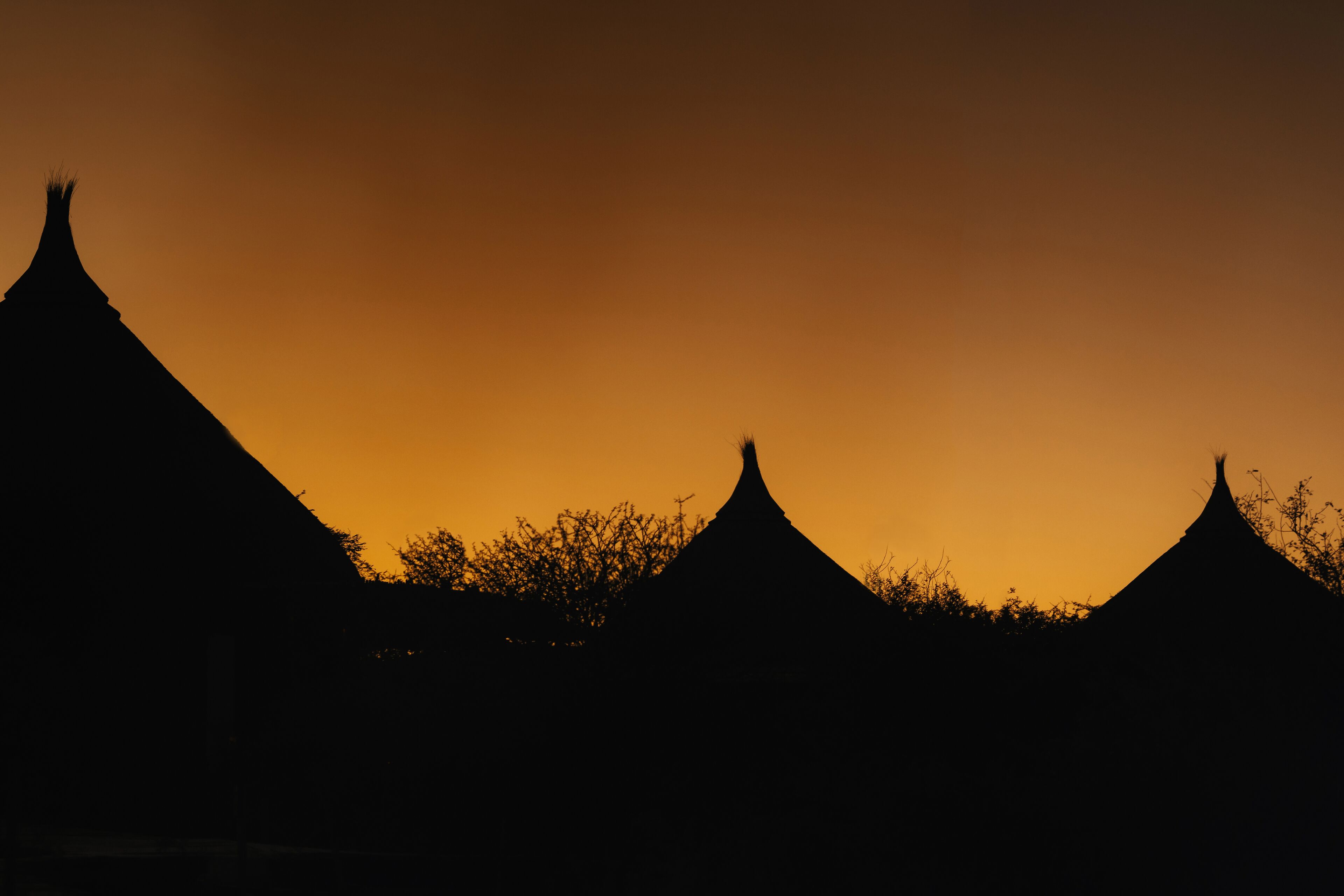 A silhouette of traditional buildings against a sunset sky.