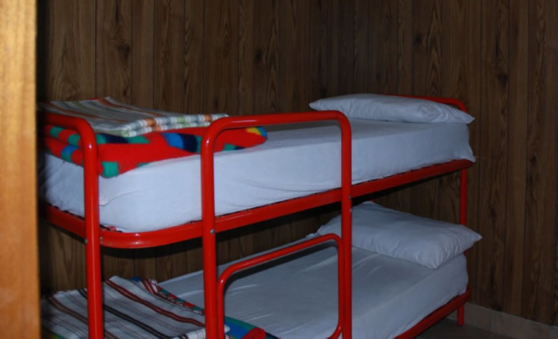 A bunk bed with white bedding and a colorful blanket.