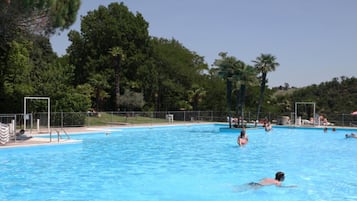 Una piscina circondata da alberi e da una recinzione.