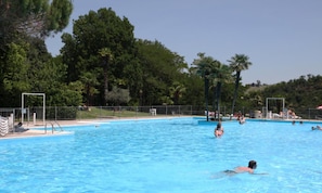 A swimming pool surrounded by trees and a fence.
