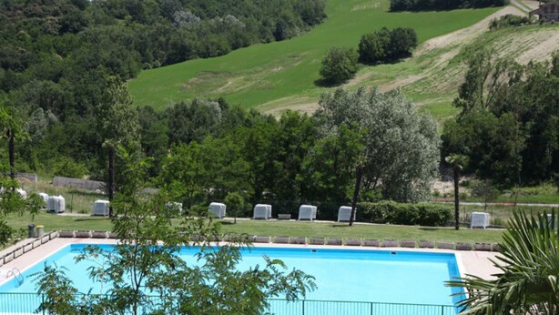 Piscina con vista su un paesaggio collinare e alberi.