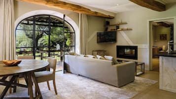 A living room with a sofa, TV, wooden beams, and a large window.