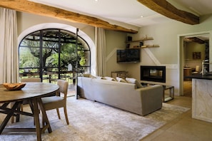 Sala de estar con sofá, televisión, vigas de madera y un ventanal grande.