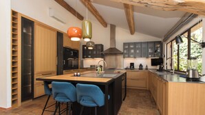 Una cocina moderna con una isla central, taburetes de bar e iluminación colgante.