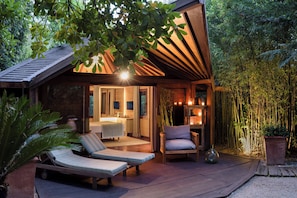 A wooden cabin with a balcony, a lounge chair, a small table, and a potted plant. - Domaine Les Mésanges (Gassin)