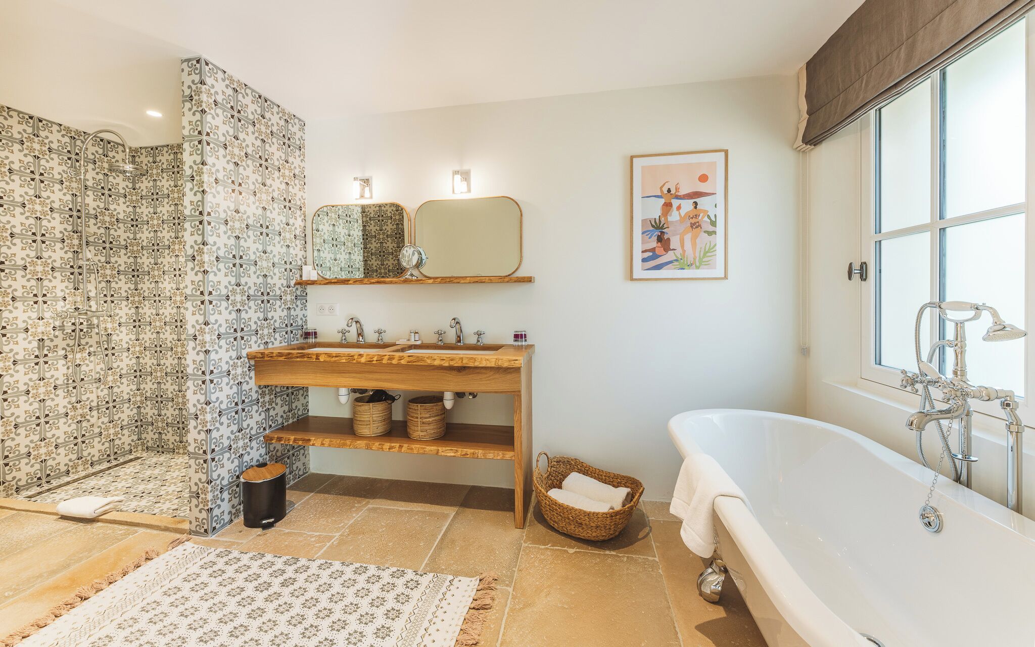Un baño con una bañera independiente, un tocador de madera con espejo y azulejos estampados en las paredes.