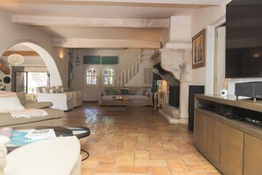 A spacious living area with a fireplace, a staircase, and a television. - Domaine Les Mésanges (Gassin)