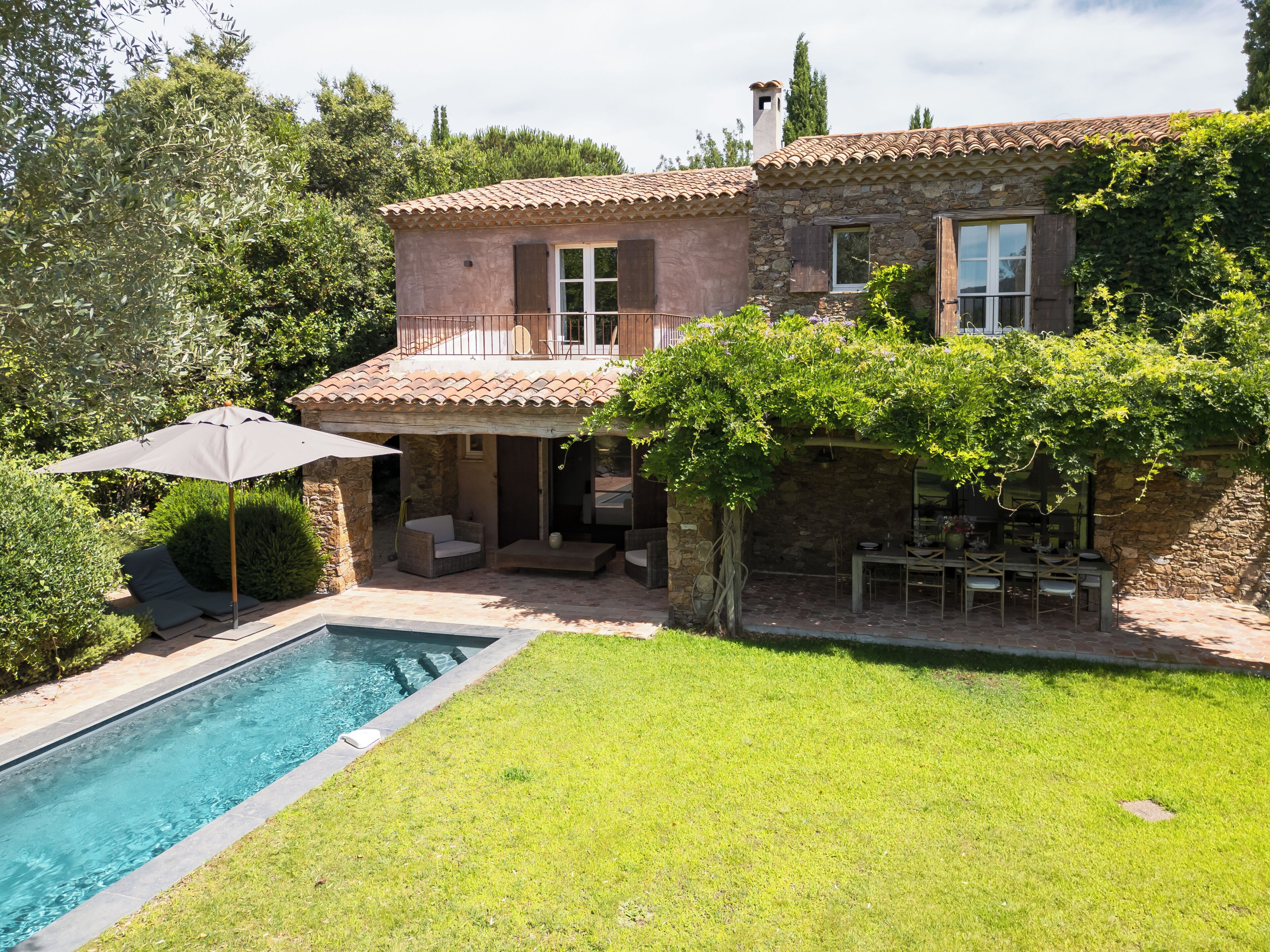 Una casa de piedra con piscina, zona de estar exterior y patio cubierto.