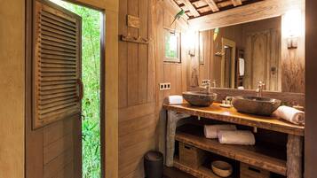 A wooden bathroom with a large window, wooden vanity, and a mirror.