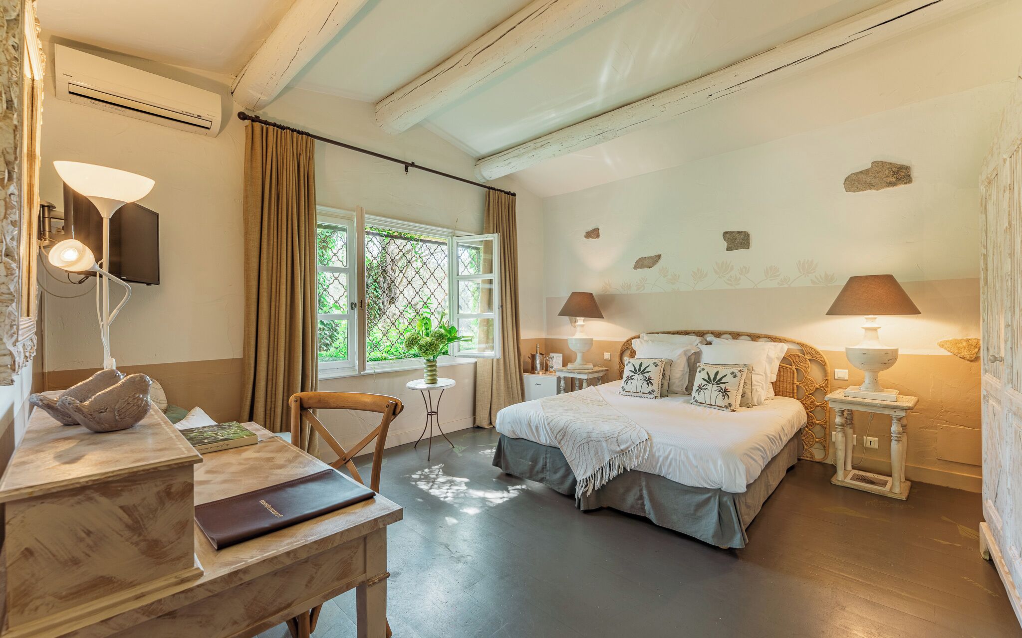 Een slaapkamer met een bed, nachtkastjes, een bureau, een stoel en een raam met gordijnen.