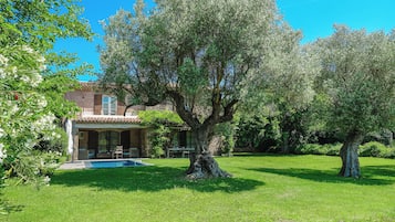 A house with a swimming pool, surrounded by lush greenery and trees.