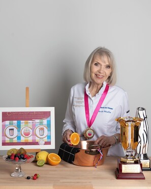 A person seated at a table with a trophy, a framed certificate, and a fruit bowl. - Domaine Les Mésanges (Gassin)