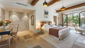 Un dormitorio con cama, mesitas de noche, una silla y vistas al exterior.