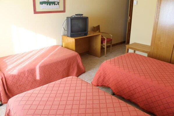 Hotellihuone, jossa on kaksi sänkyä, työpöytä, jossa on televisio, ja tuoli.