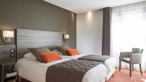 A hotel room with two beds, a nightstand, a chair, and a large window with curtains. - Hôtel Restaurant SPA Les Soldanelles (Fontcouverte-la-Toussuire)
