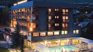 A multi-story hotel with a swimming pool and lounge chairs. - Hôtel Restaurant SPA Les Soldanelles (Fontcouverte-la-Toussuire)
