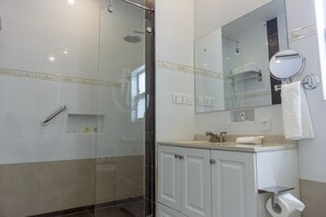 A modern bathroom with a glass-enclosed shower, white cabinetry, and a large mirror. - Frederick's Lodge (Kumasi)