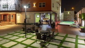 An outdoor patio area with a pool, seating arrangements, and a reception desk. - Frederick's Lodge (Kumasi)